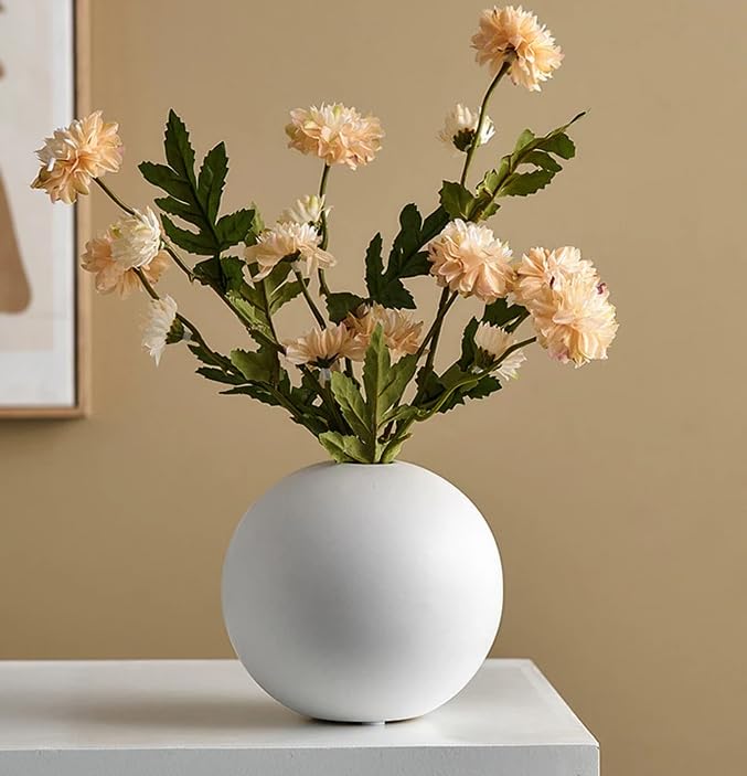 White vase with colorful flowers on wooden table.