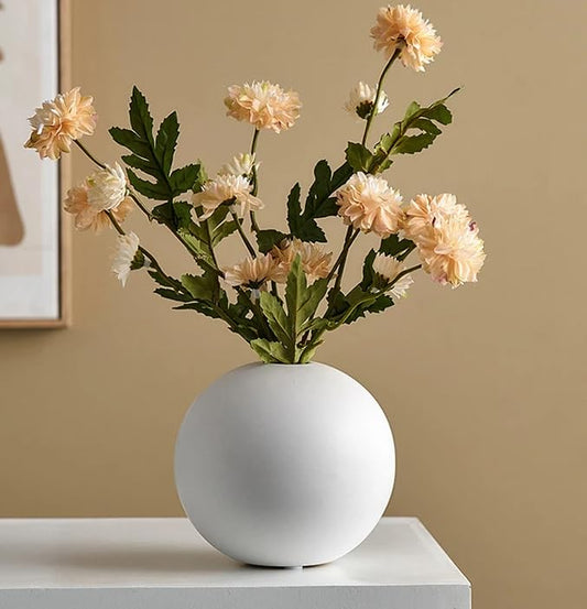 White vase with colorful flowers on wooden table.