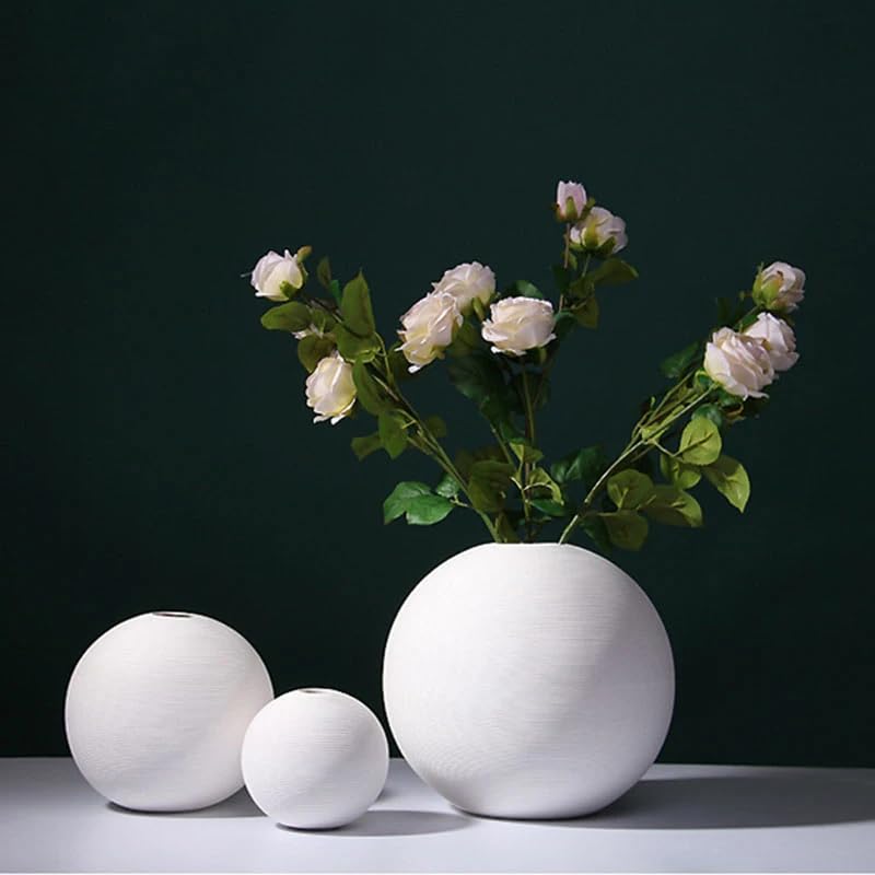 Three white vases filled with colorful flowers.
