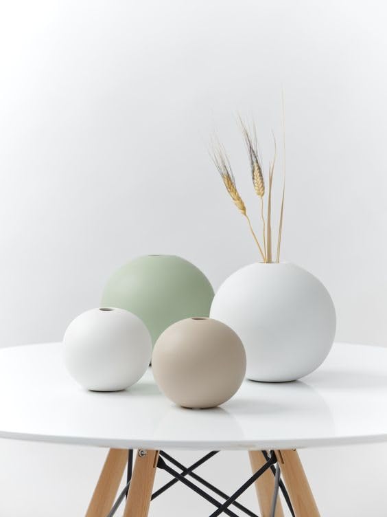 Three white and green vases on a table, perfect for adding a touch of elegance to any room decor.