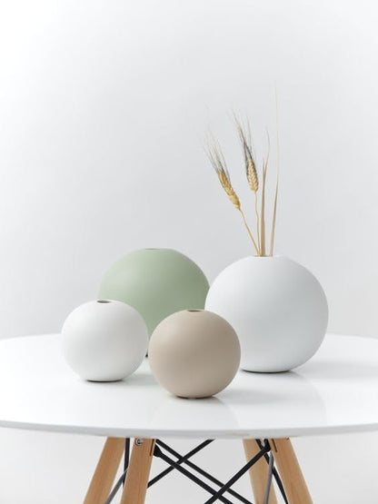 Three white and green vases on a table, perfect for adding a touch of elegance to any room decor.