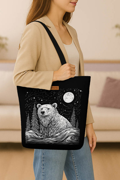 A black tote bag adorned with a bear and trees, highlighting a rustic outdoor theme.
