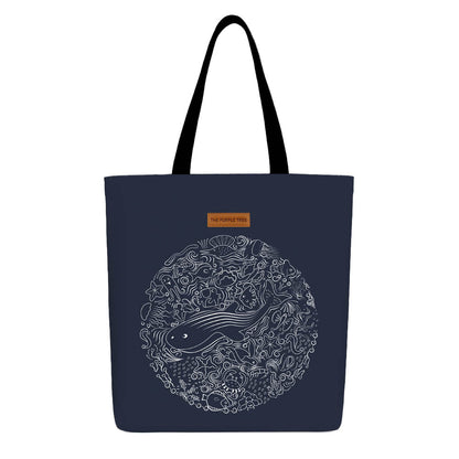 A blue tote bag featuring a whimsical illustration of a whale swimming gracefully.