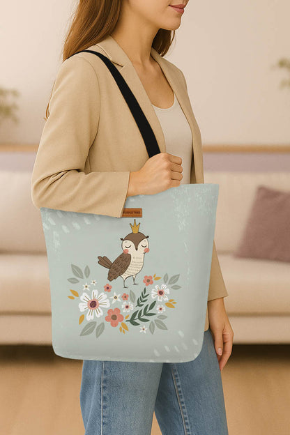 A stylish tote bag adorned with an owl and blooming flowers, showcasing a whimsical design.