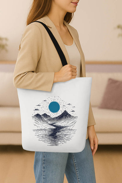 A tote bag adorned with a mountain scene illuminated by a striking blue moon.