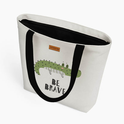 Stylish tote bag with a bold crocodile graphic, promoting a message of bravery and adventure.