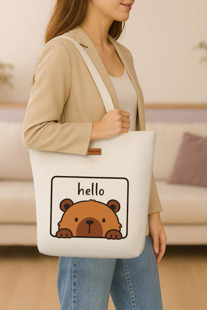 A stylish tote bag adorned with a cheerful bear graphic and the greeting "hello."